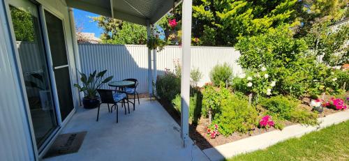 a porch with a table and chairs and flowers at Seaside Aura in Victor Harbor