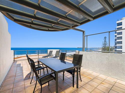 a table and chairs on a balcony with the ocean at Meridian Alex Beach Apartments in Alexandra Headland