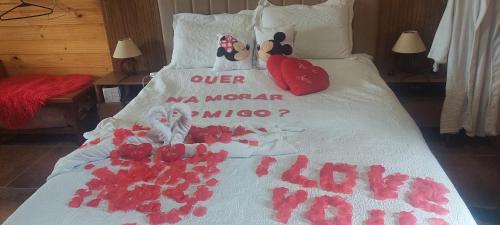 a bed with red rose petals on it at Chale com hidromassagem Casa Papai Noel in Campos do Jordão