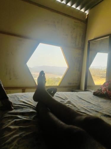 a person laying on a bed looking out a window at Hotel Yogiraj in Jāmb