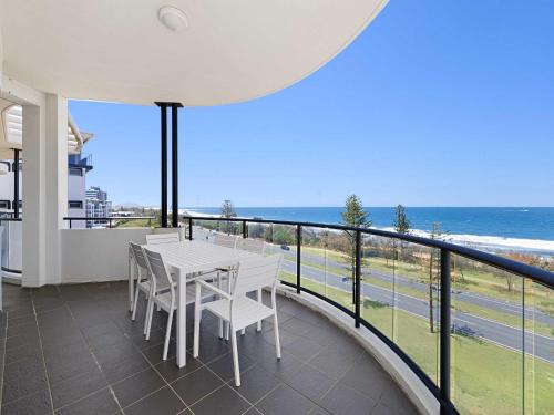 a balcony with a table and chairs and the ocean at Meridian Alex Beach Apartments in Alexandra Headland