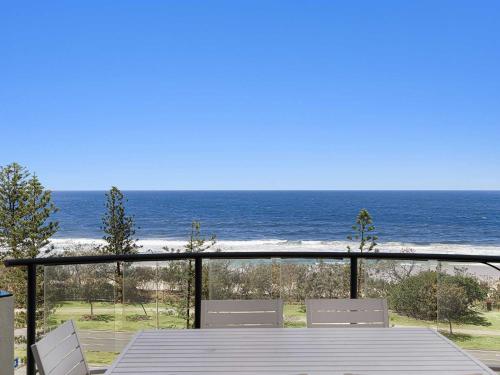 a table and chairs on a balcony with the ocean at Meridian Alex Beach Apartments in Alexandra Headland