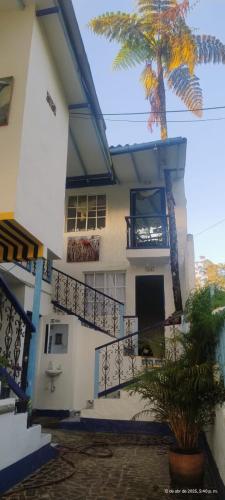 a house with a palm tree in front of it at Vista Farallones Hostel in Jardin