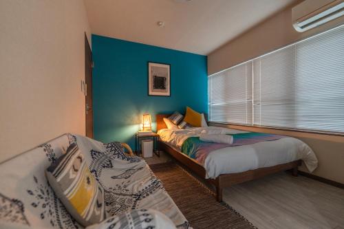 Un dormitorio con dos camas y una pared azul. en 夏風-なつバル-, en Isla Miyako