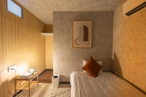 Un dormitorio con una cama y una mesa con una lámpara. en 夏風-なつバル-, en Isla Miyako