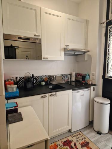 une cuisine avec des armoires blanches et un évier dans l'établissement Studio de charme Paris Champs Elysees, à Paris