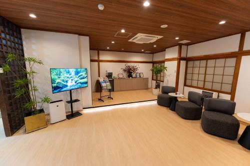 a lobby with chairs and a flat screen tv at Komakusa Hotel in Matsumoto