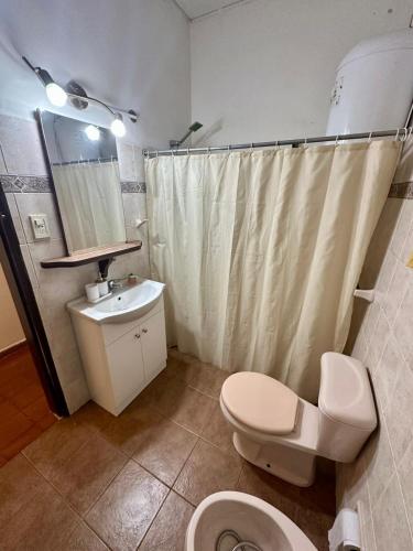 a bathroom with a toilet sink and a shower curtain at Apapacho Urbano in Paysandú