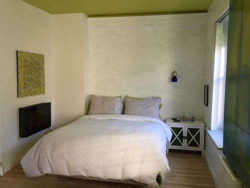 1 dormitorio con 1 cama blanca y TV en Le 253 en Quebec