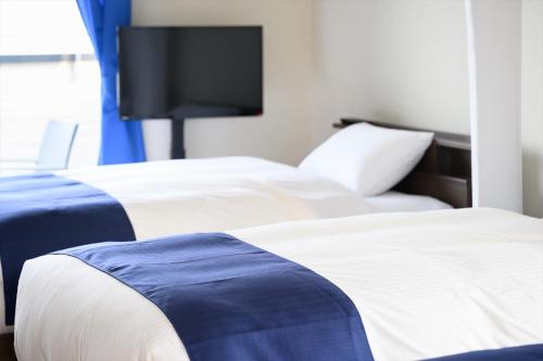 two beds in a hotel room with a flat screen tv at 青の宿 The Blue Villa まるで映画のような開放感あふれるオーシャンビュー Open ocean view like in a movie 駐車場2台有り Supported by COCOSTAY in Iwakuni