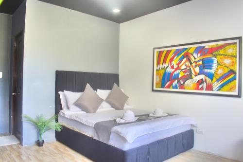 a bedroom with a bed with a painting on the wall at Cozy Crib Saratoga in Tagaytay Midlands with Breakfast in Tagaytay