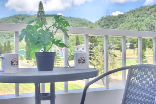 a table with a plant and mugs on a balcony at Cozy Crib Saratoga in Tagaytay Midlands with Breakfast in Tagaytay