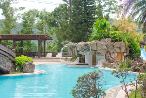 a swimming pool in a resort with a waterfall at Cozy Crib Saratoga in Tagaytay Midlands with Breakfast in Tagaytay