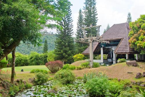 a garden in front of a house with a pond at Cozy Crib Saratoga in Tagaytay Midlands with Breakfast in Tagaytay
