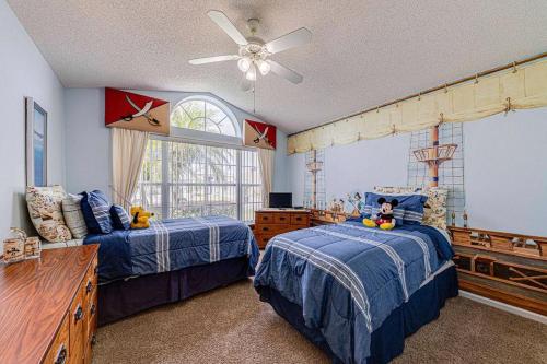 Un dormitorio con dos camas y un ventilador de techo. en Pool Therapy - New Pool Home, en Orlando