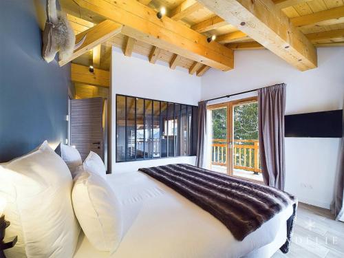 une chambre avec un grand lit et une grande fenêtre dans l'établissement Appartement de luxe 8 pers. avec cheminée, parking, proche pistes et commerces - FR-1-398-683, à Montvalezan