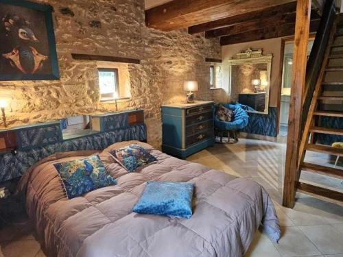 a bedroom with a large bed and a stone wall at Gîte 8 personnes avec cheminée et SPA à Biron - FR-1-616-481 in Biron