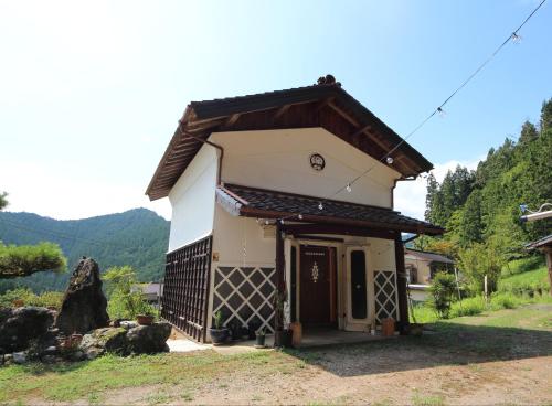 a small white house with a roof at Kura Retreat Guest House in Hongō