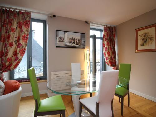 une salle à manger avec une table en verre et des chaises vertes dans l'établissement Appartement T3 4 pers, Centre La Bourboule, Parking, WiFi, Chien admis - FR-1-608-293, à La Bourboule