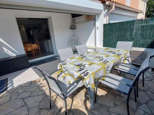 une table et des chaises jaunes et blanches sur une terrasse dans l'établissement Maison mitoyenne 3 pièces avec terrasse et parking privé - FR-1-326-855, à Marseillan