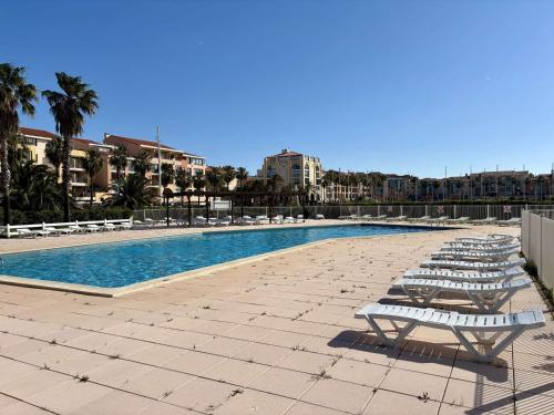 - une piscine avec des chaises longues à côté d'un complexe dans l'établissement Appartement 2 pièces à Argelès-sur-Mer avec piscine - FR-1-225-831, à Argelès-sur-Mer