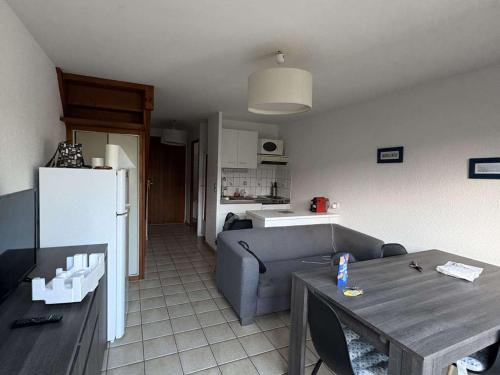 Il dispose d'une cuisine et d'un salon avec un canapé et une table. dans l'établissement Maison calme proche plage et commerces - FR-1-831-13, à Biscarrosse