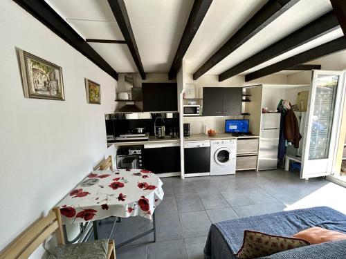 une cuisine avec une table et une cuisine avec une cuisinière dans l'établissement Pavillon avec mezzanine, terrasse ensoleillée, WIFI et parking à Argelès-sur-Mer - FR-1-388-240, à Argelès-sur-Mer