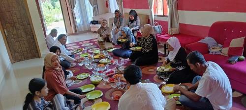 a group of people sitting around a table eating at Zhafran homestay syari'ah in Sarilamak