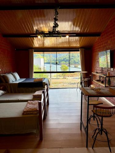 a bedroom with two beds and a large window at Pousada Refúgio das Águas Quarto 4 in Chapecó
