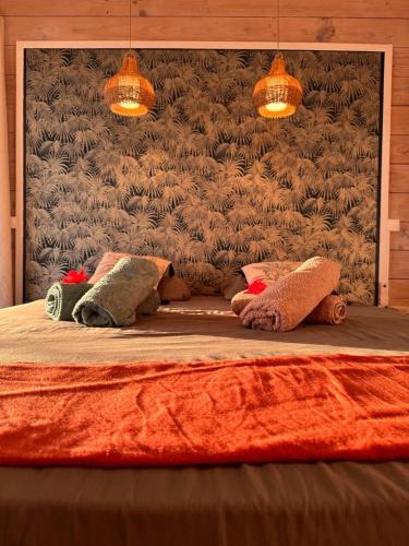 a bed with two pillows on it with two lights at Villa Teana, avec piscine et vue lagon in Taoru