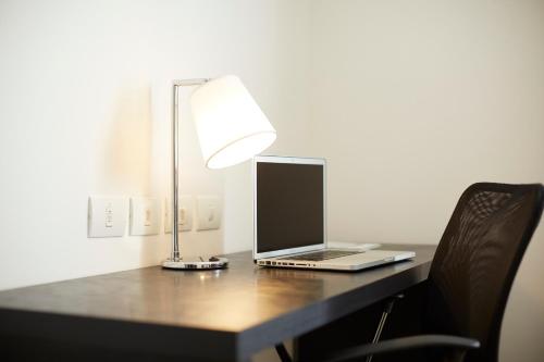 a laptop computer sitting on a desk with a lamp at Tulip Inn Itaguai in Itaguaí
