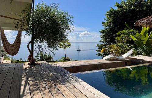 a pool with a hammock and a view of the water at Villa Teana, avec piscine et vue lagon in Taoru