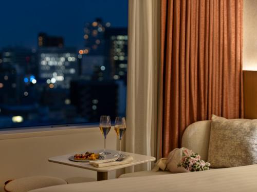 a hotel room with a table with two glasses of wine at Mitsui Garden Hotel Sendai - Reopening on June 14 in Sendai