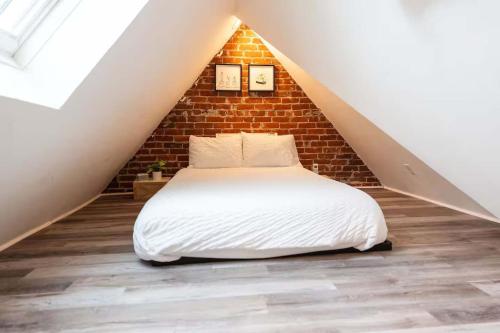 a bed in a loft with a brick wall at Jennifer's Unique Loft Near Brown 2 Parking Spots in Providence