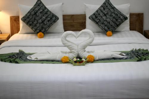a bed with two swans made out of towels at Hanaka Riverside Ubud in Ubud