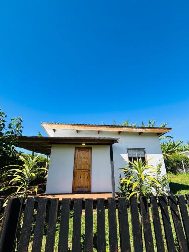 a small white house with a wooden door at Cabañas Tea Tea en Hanga Roa in Hanga Roa