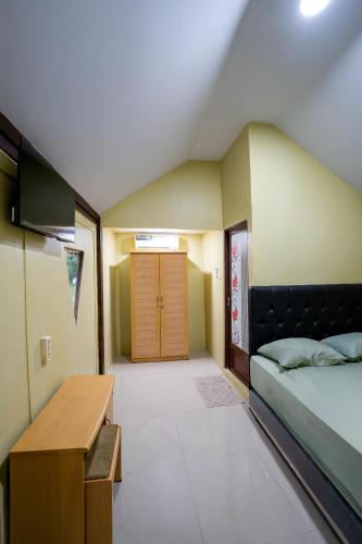 a bedroom with a bed and a desk and a door at De Gentong Guest House & Cafe By Akasha in Dadapan