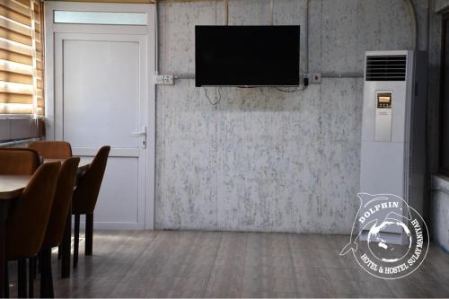 a room with a television on a wall with a table at Dolphin Hotel & Hostel in As Sulaymānīyah