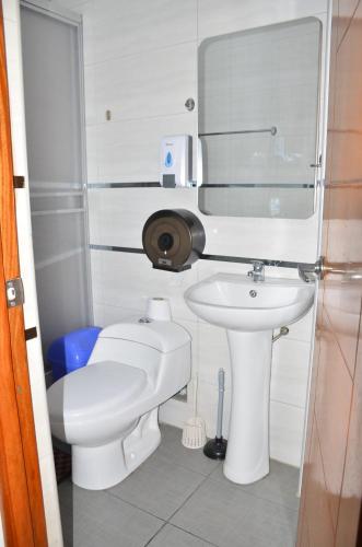a bathroom with a white toilet and a sink at Makalu Lodge in Huaraz