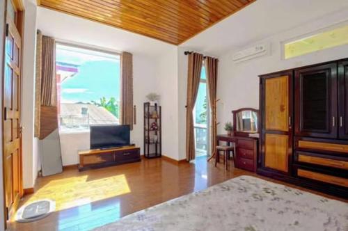 un salon avec une télévision et une grande fenêtre dans l'établissement T'Homestay garden villa, à Thôn Lại Thê