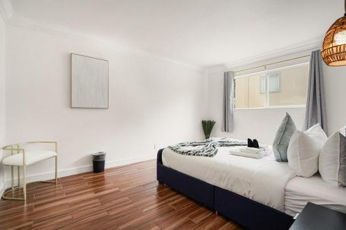 a white bedroom with a bed and a chair at Stunning 2BR with Ocean, Mountain & Sunset Views in Pacifica
