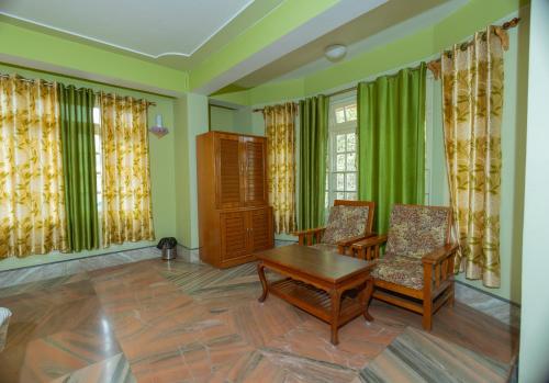 a living room with green walls and a table and chairs at Divyaraa Breathing Stone in Kalimpong
