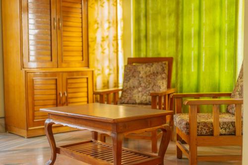a room with a table and chairs and a green wall at Divyaraa Breathing Stone in Kalimpong