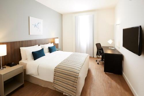 a hotel room with a large bed and a desk at Tulip Inn Itaguai in Itaguaí