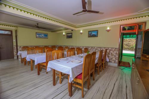 a dining room with white tables and wooden chairs at Divyaraa Breathing Stone in Kalimpong