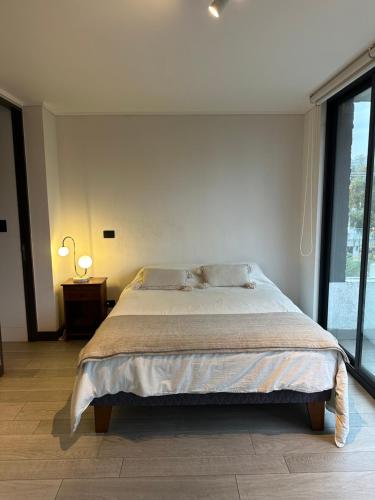 a bedroom with a large bed and a large window at Elegante departamento in Santiago