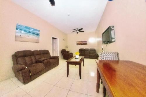 a living room with a couch and a tv at Dela de-Rose Guest House Negril Jamaica in Negril