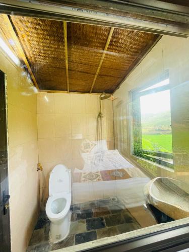 a bathroom with a toilet and a window at Quế Homestay in Hòa Bình