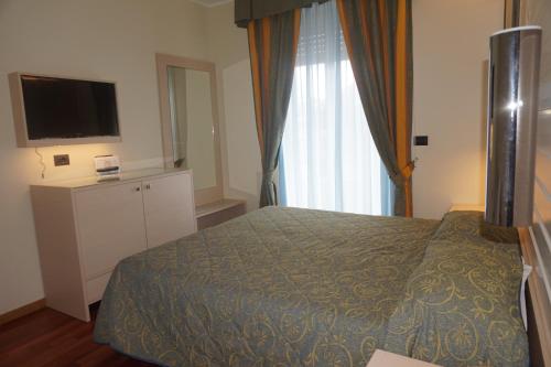 a hotel room with a bed and a television at Hotel Columbus in Lignano Sabbiadoro