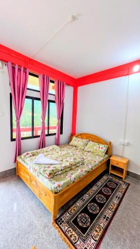 a bedroom with a bed and a window with pink curtains at Lhamu homestay in Chug